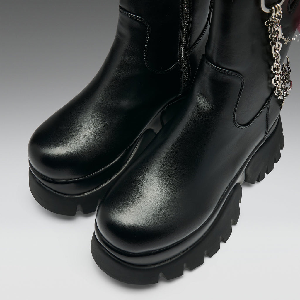 A pair of black leather ankle boots with chunky lug soles and a silver chain detail, shown on a neutral gray background.