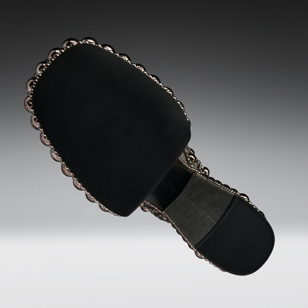 A black fabric-covered shoe sole with a decorative scalloped metallic edge and a dark gray cushioned section, shown on a gradient gray background.