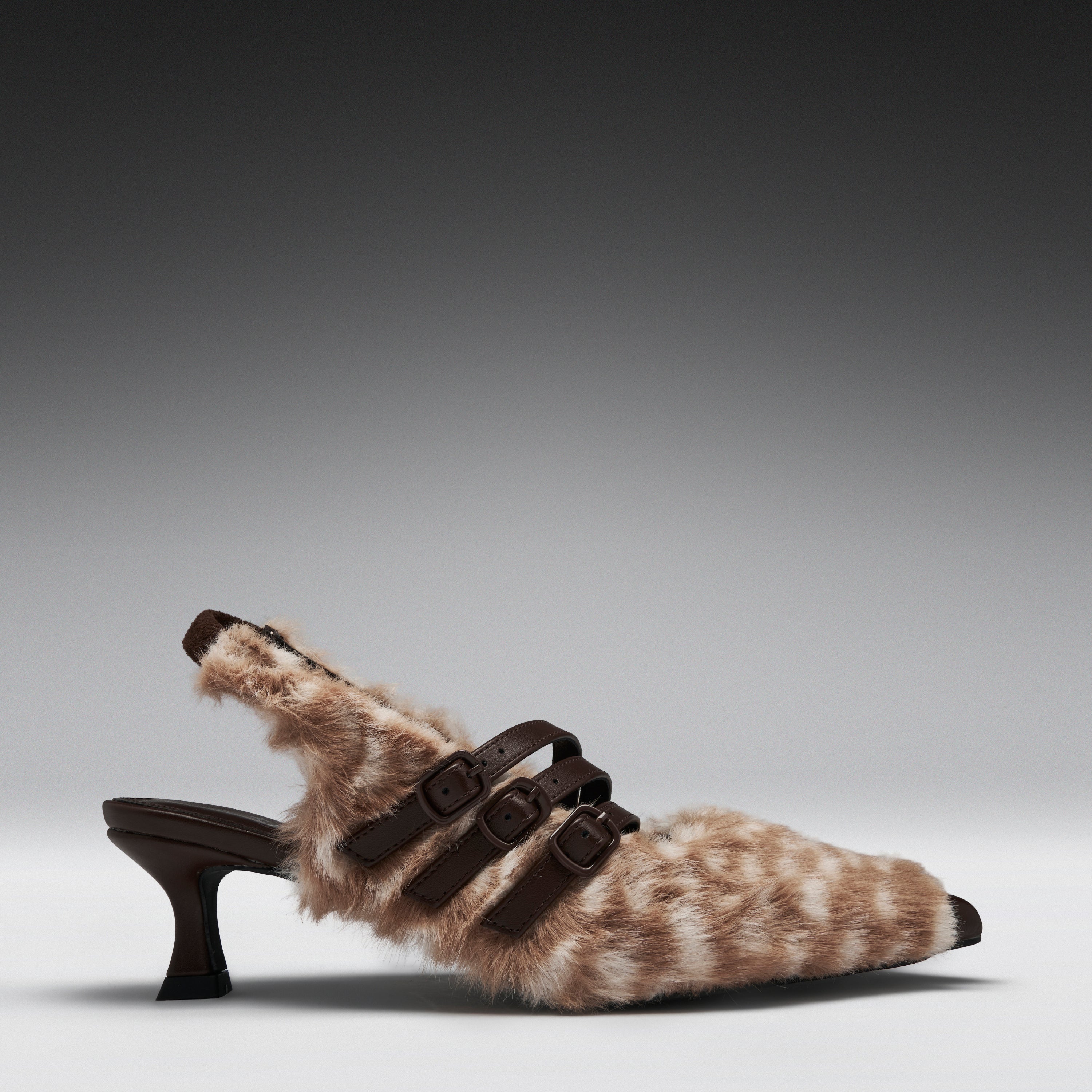 A single women's kitten heel with a brown and beige animal-print faux fur upper, dark brown buckle straps, and a dark brown block heel, shown against a gray gradient studio background.