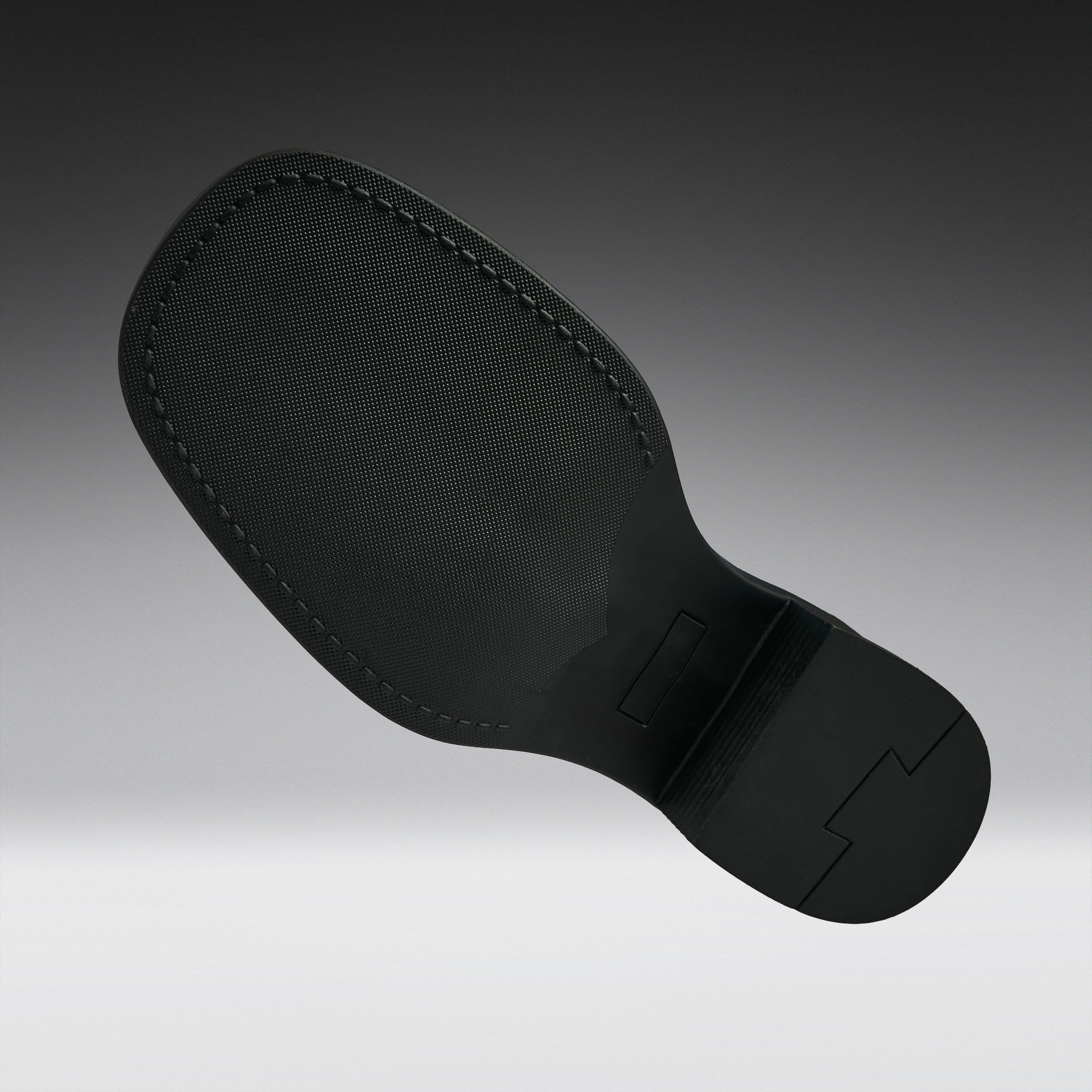 A black textured shoe sole with visible stitching and molded tread details, shown floating against a dark-to-light gray gradient background.