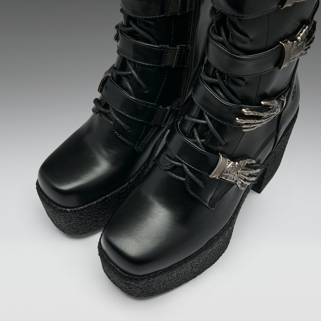 Black platform ankle boots with multiple strap buckles, lace-up front, and silver claw-shaped hardware, photographed on a light gray studio background.