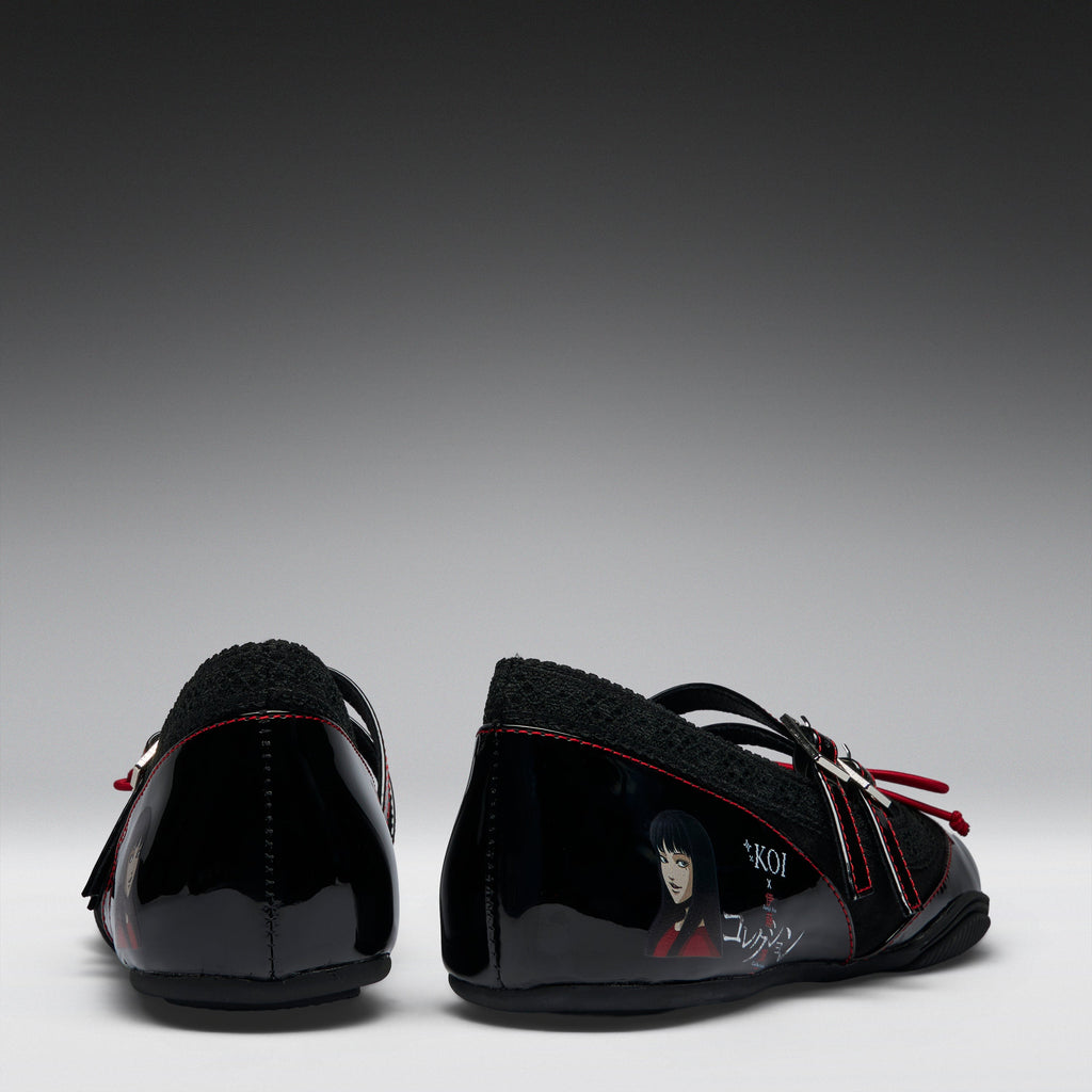 A pair of black patent leather Mary Jane shoes with black fleece lining, red contrast stitching, and character graphics on the sides, shown from the back against a gradient gray background.