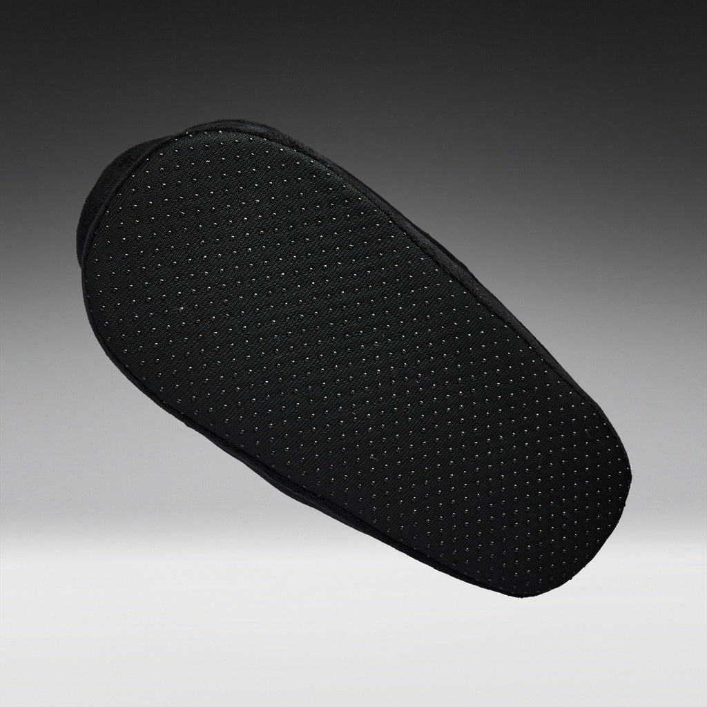 A black textured shoe cushion with a perforated grip pattern, shown floating against a dark gray gradient background.