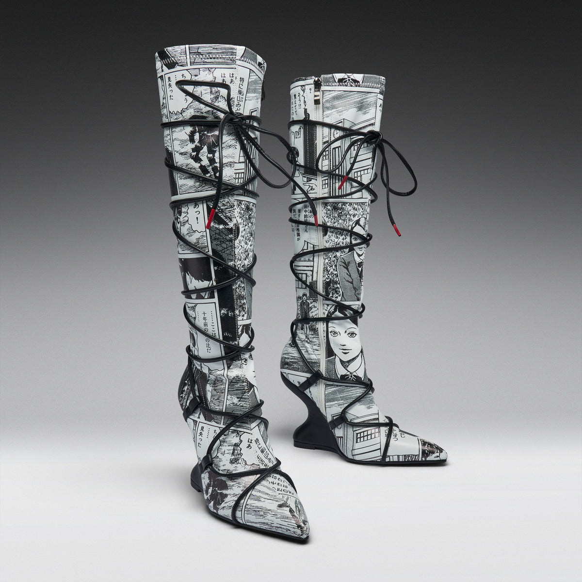 A pair of thigh-high pointed-toe boots with a black and white newspaper collage print, wrapped in black lace up to the ankles, shown on a gray gradient studio background.