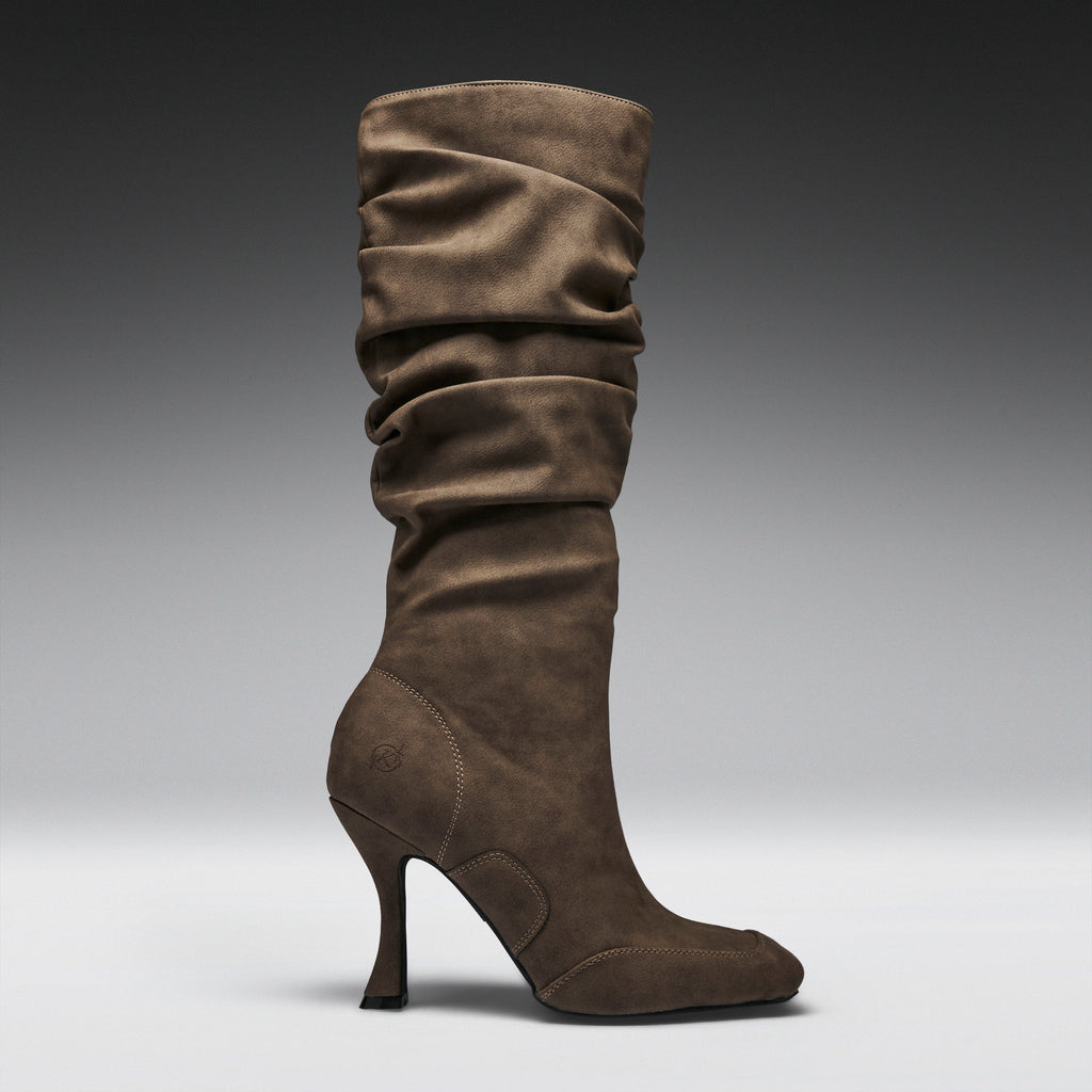 A single mid-calf heeled boot in brown suede, shown in profile against a dark-to-light gray gradient studio background.
