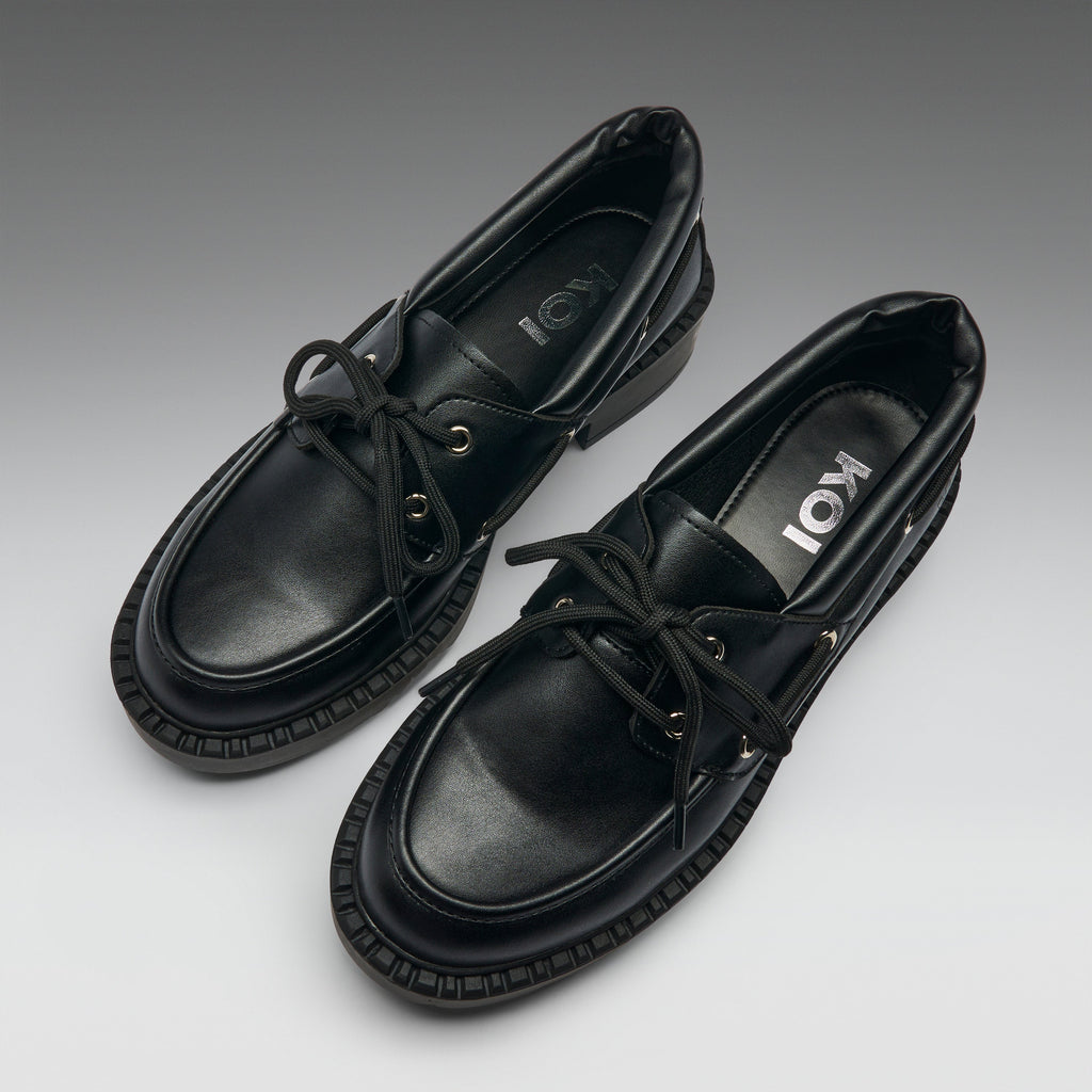 Pair of black leather shoes with brand logo on a gradient background