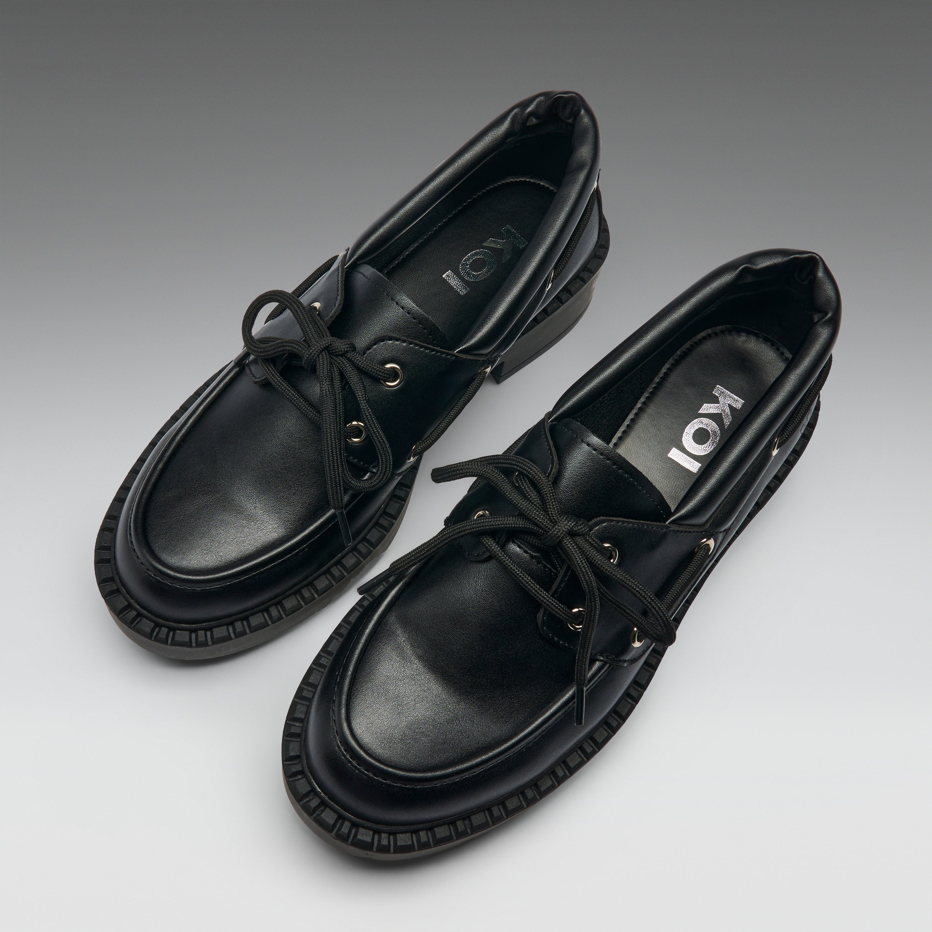 Pair of black leather shoes with brand logo on a gradient background