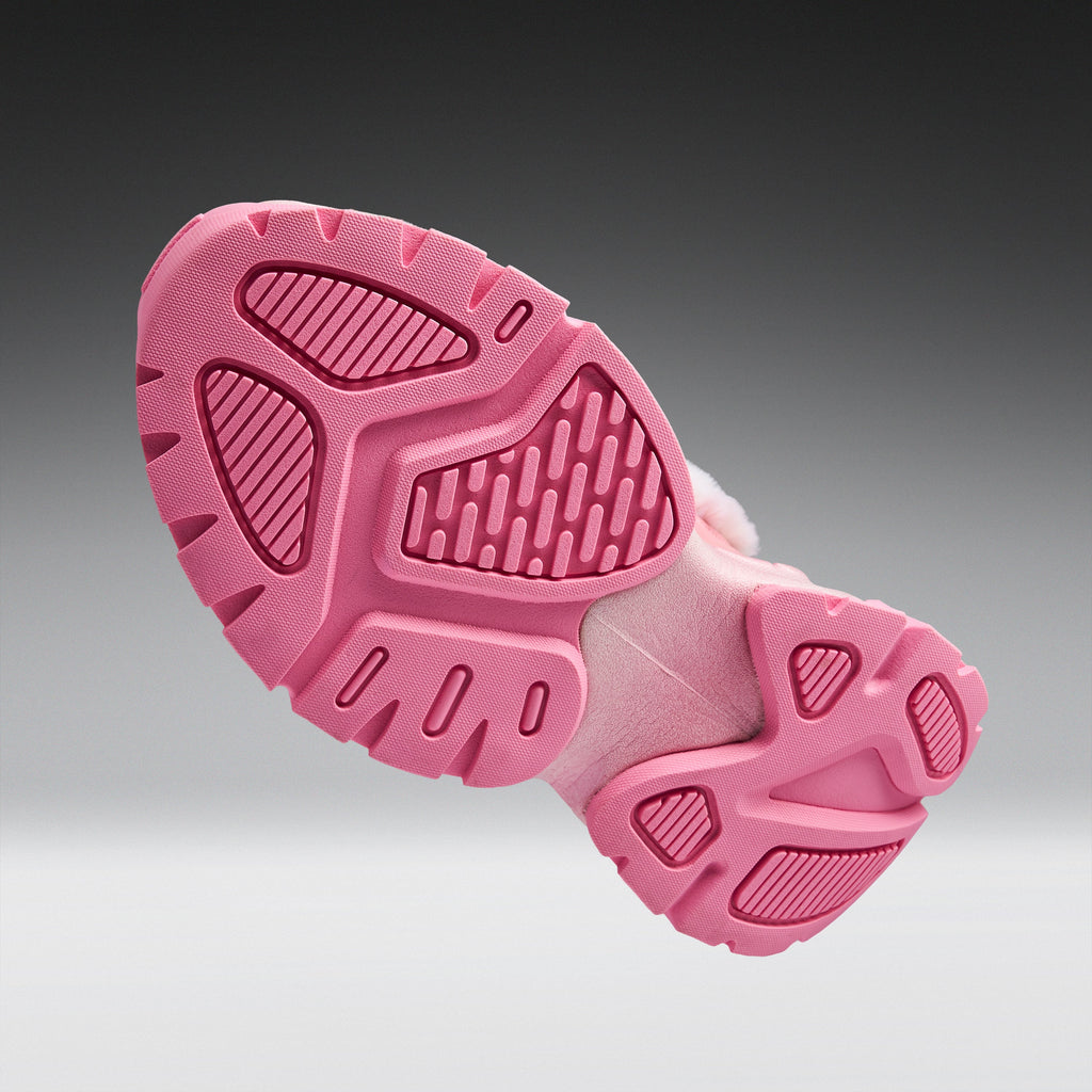 A close-up of a pink shoe sole, showing the textured tread pattern and cushioned midsole, set against a dark-to-light gray gradient background.