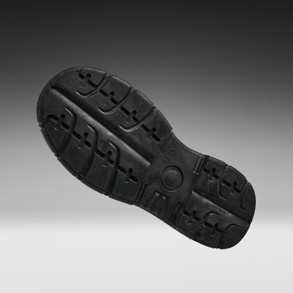 A black rubber shoe sole shown from a top-down angle against a dark gray to light gray gradient background.