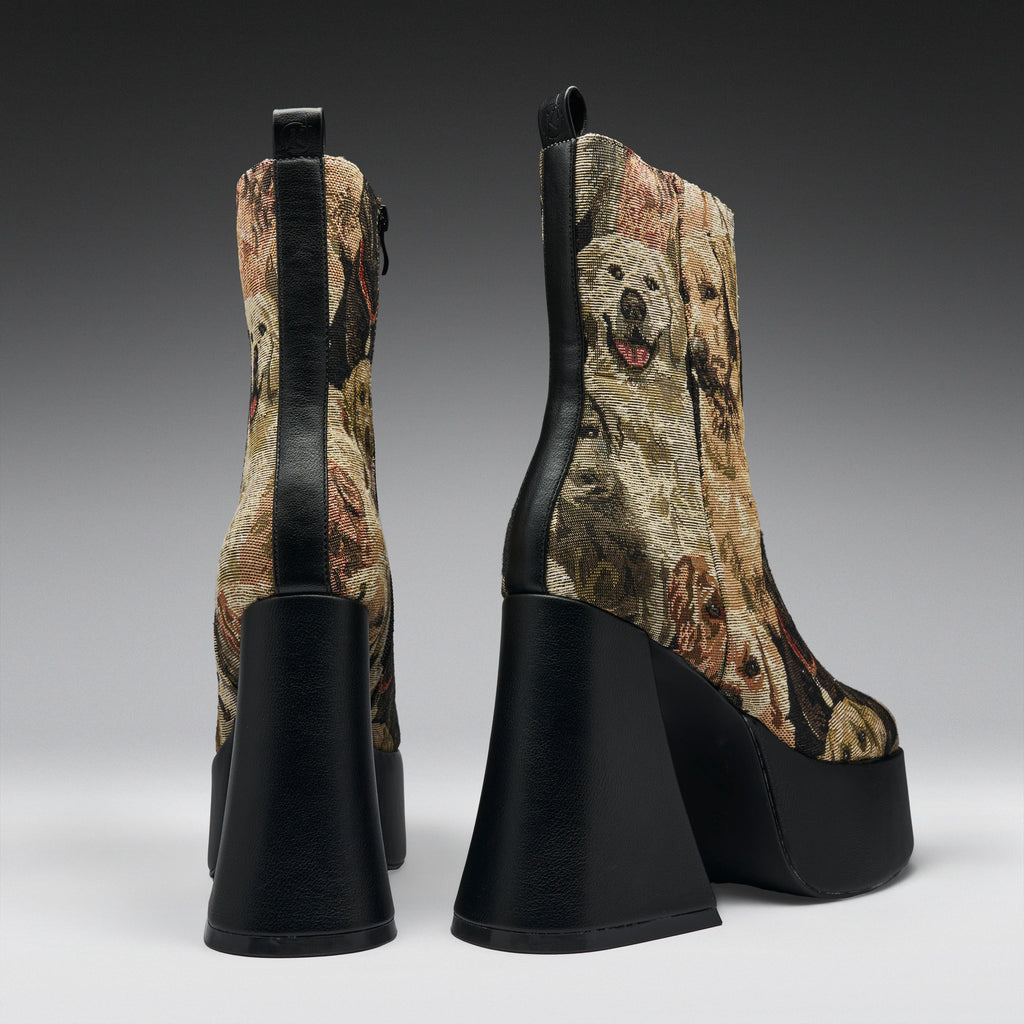A pair of high-heeled platform ankle boots shown from the back, featuring a brown and beige dog-print fabric with black leather trim and chunky black platform heels.