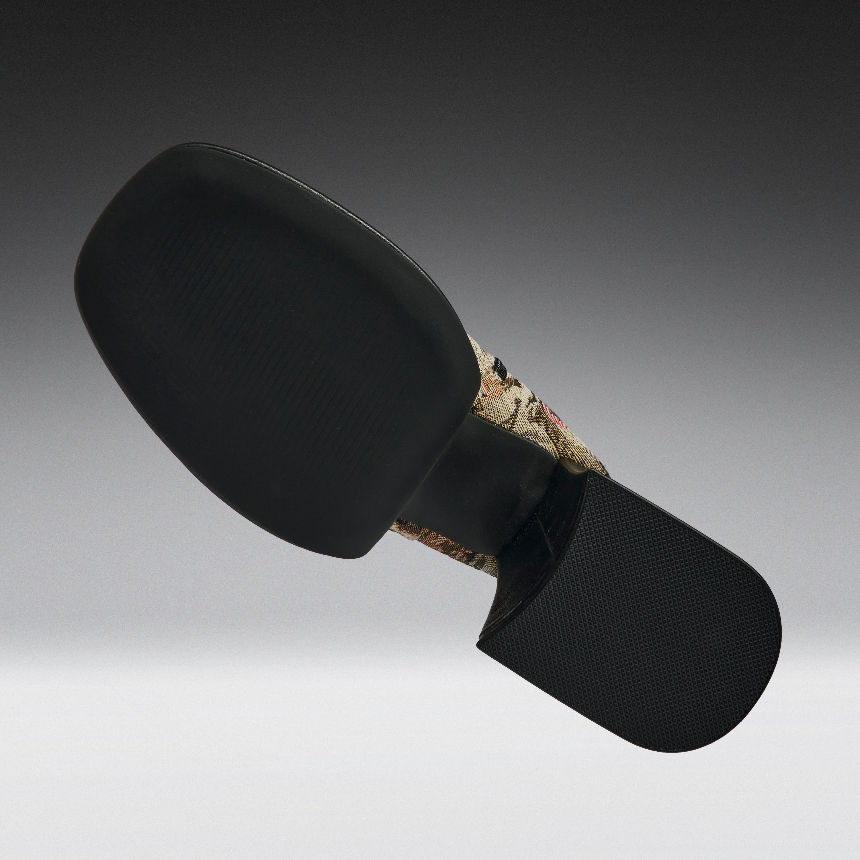 A black motorcycle or bicycle handlebar grip cover with a textured black rubber face and a camouflage-patterned stem section, shown against a dark gray gradient background.