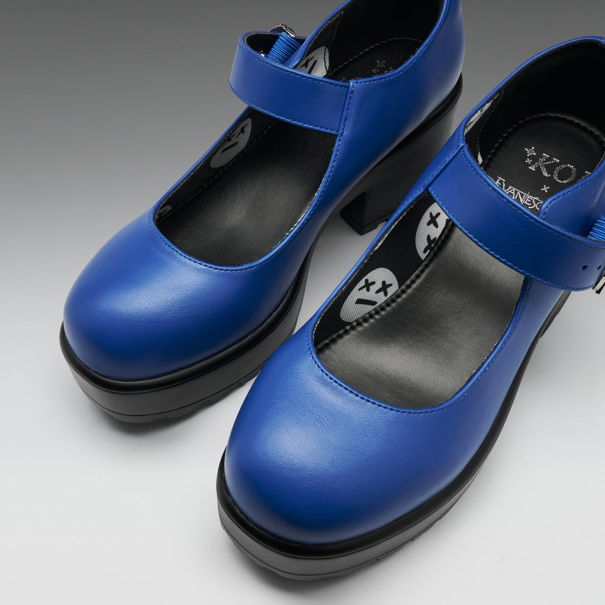 A pair of blue Mary Jane-style platform heels with black soles and black interior lining, photographed on a clean light gray studio background. The insole shows the brand name 'KOI'.