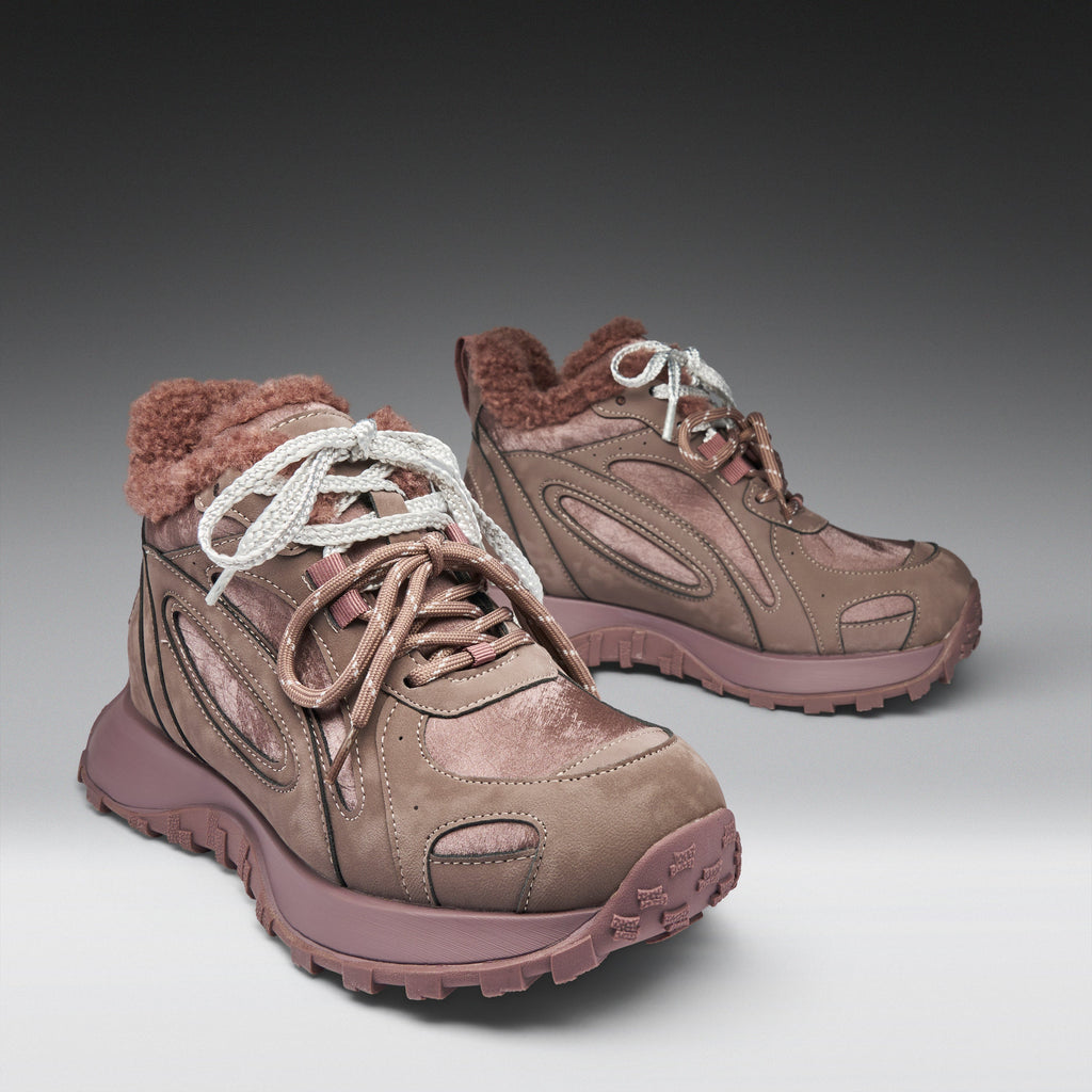 Pair of brown hiking boots with white laces on a gray background